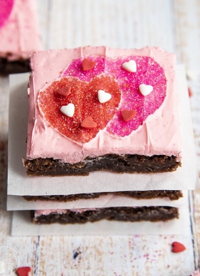 Above shot of stacked valentine's day brownies with pink frosting and heart shaped sprinkles.
