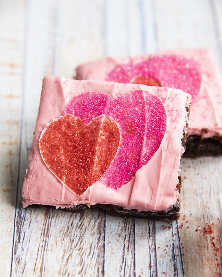 Valentine Brownies are a super easy and fun brownie topped with pink frosting and a heart pattern made with sprinkles!