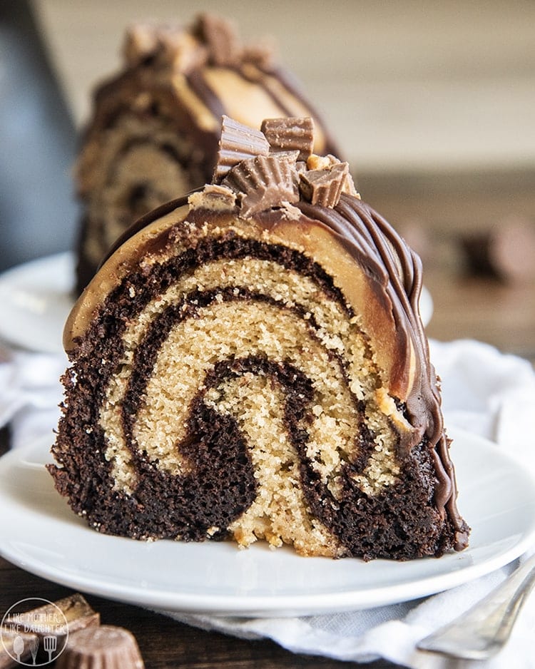 A piece of chocolate peanut butter swirled bundt cake topped with ganache and peanut butter cups on a plate.