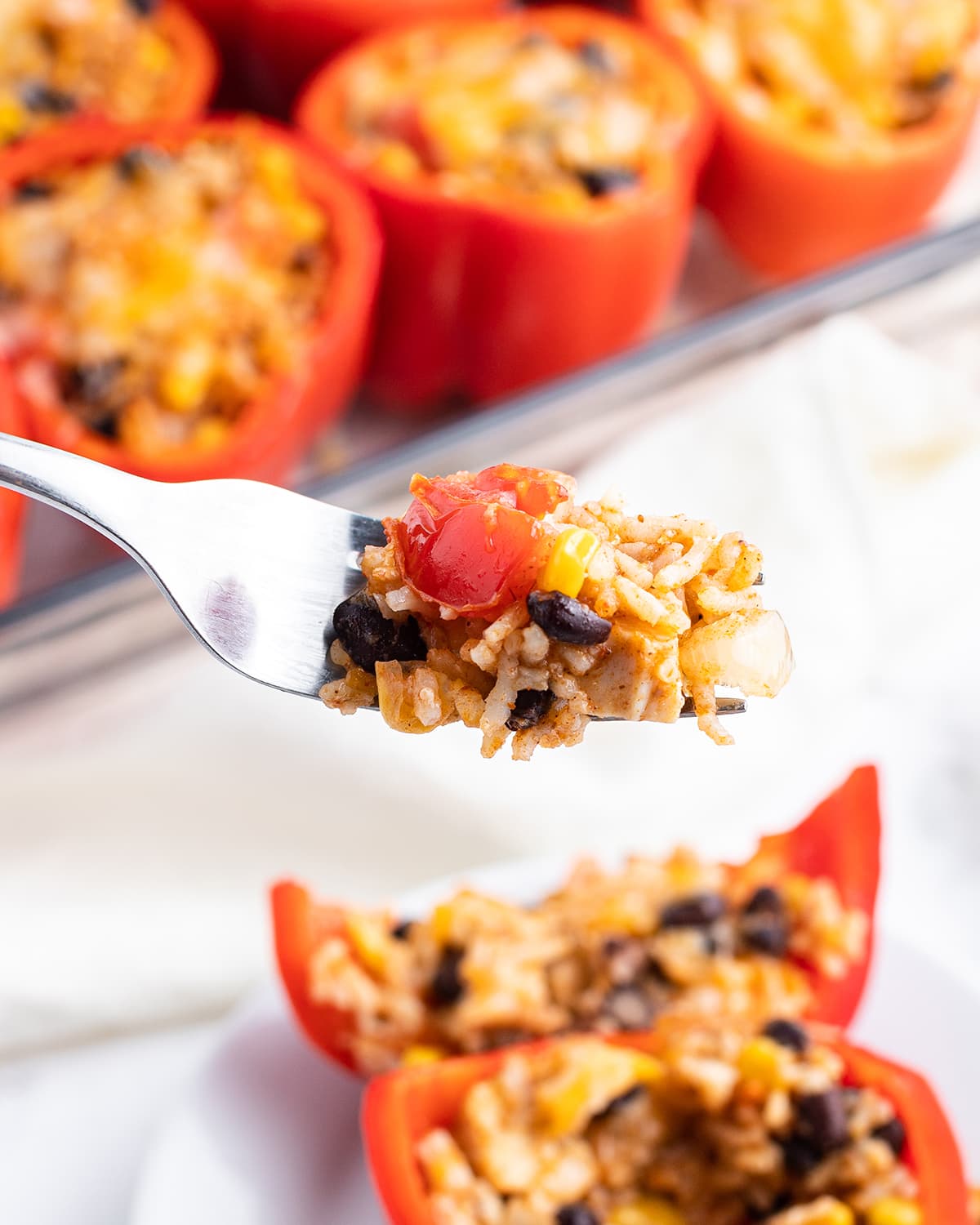 A spoonful of stuffed pepper filling on a fork above a stuffed pepper on a plate.