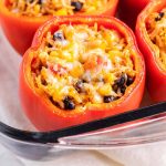 A stuffed pepper topped with cheese in a glass baking pan.
