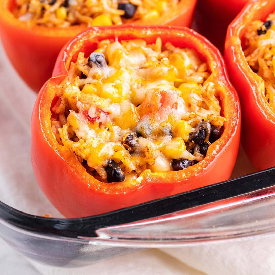 A stuffed pepper topped with cheese in a glass baking pan.