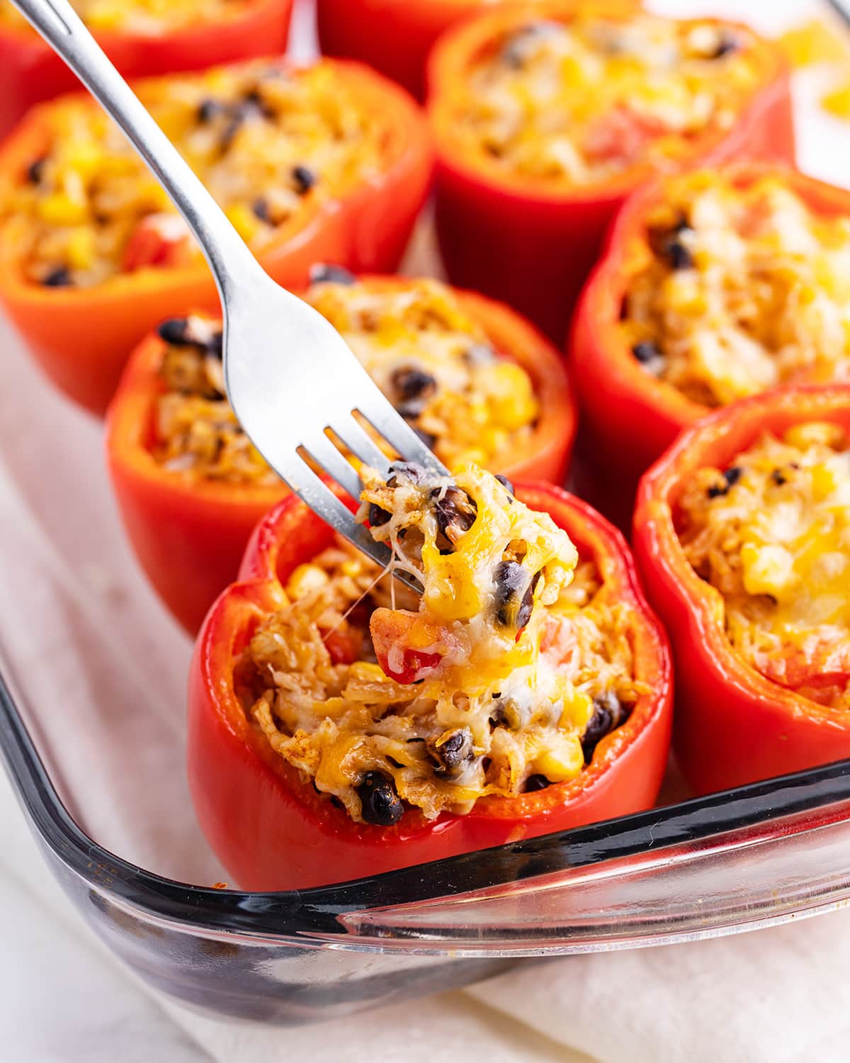 A fork digging into a stuffed pepper in a pan.