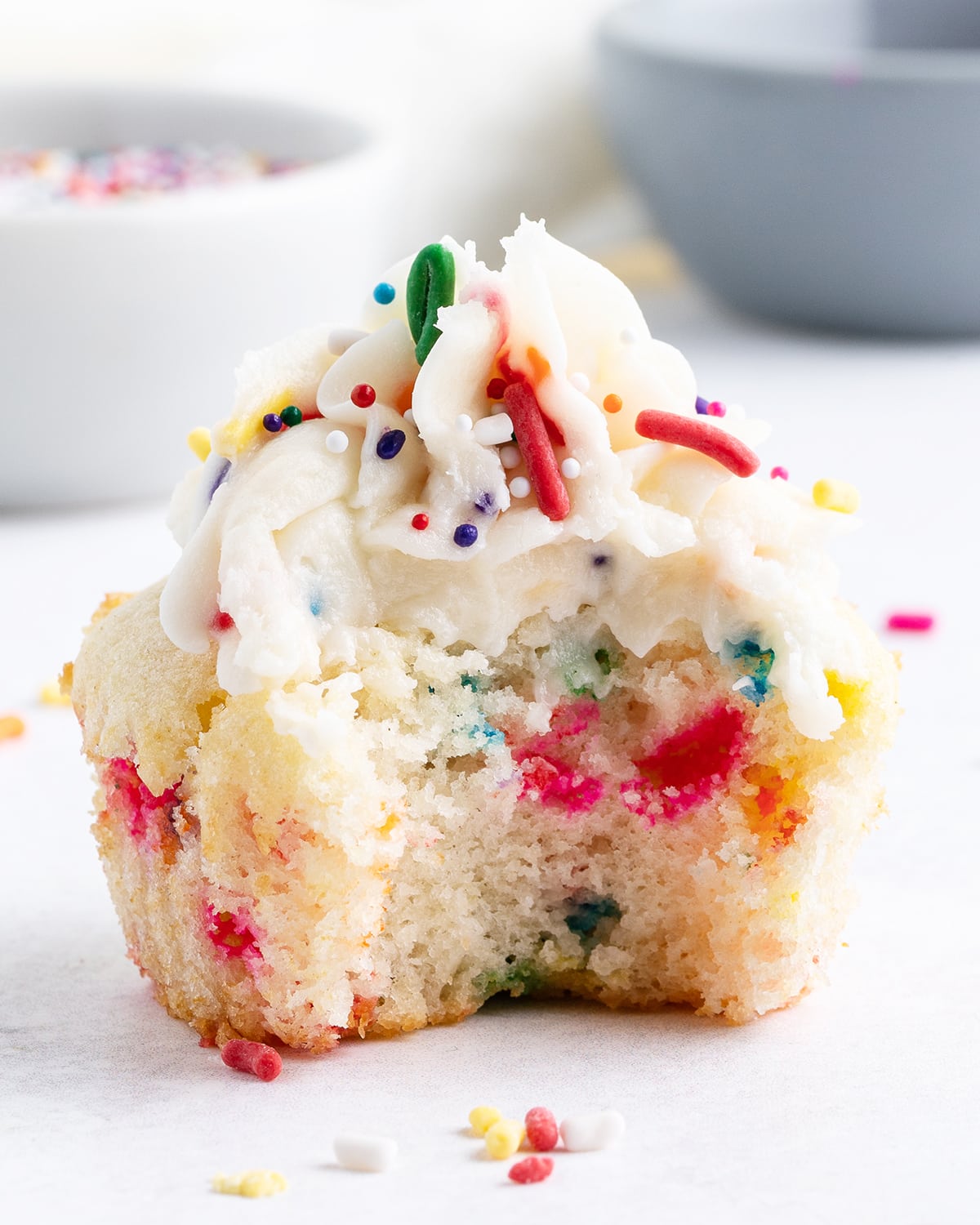 A cupcake with sprinkles, and a bite taken out of it.