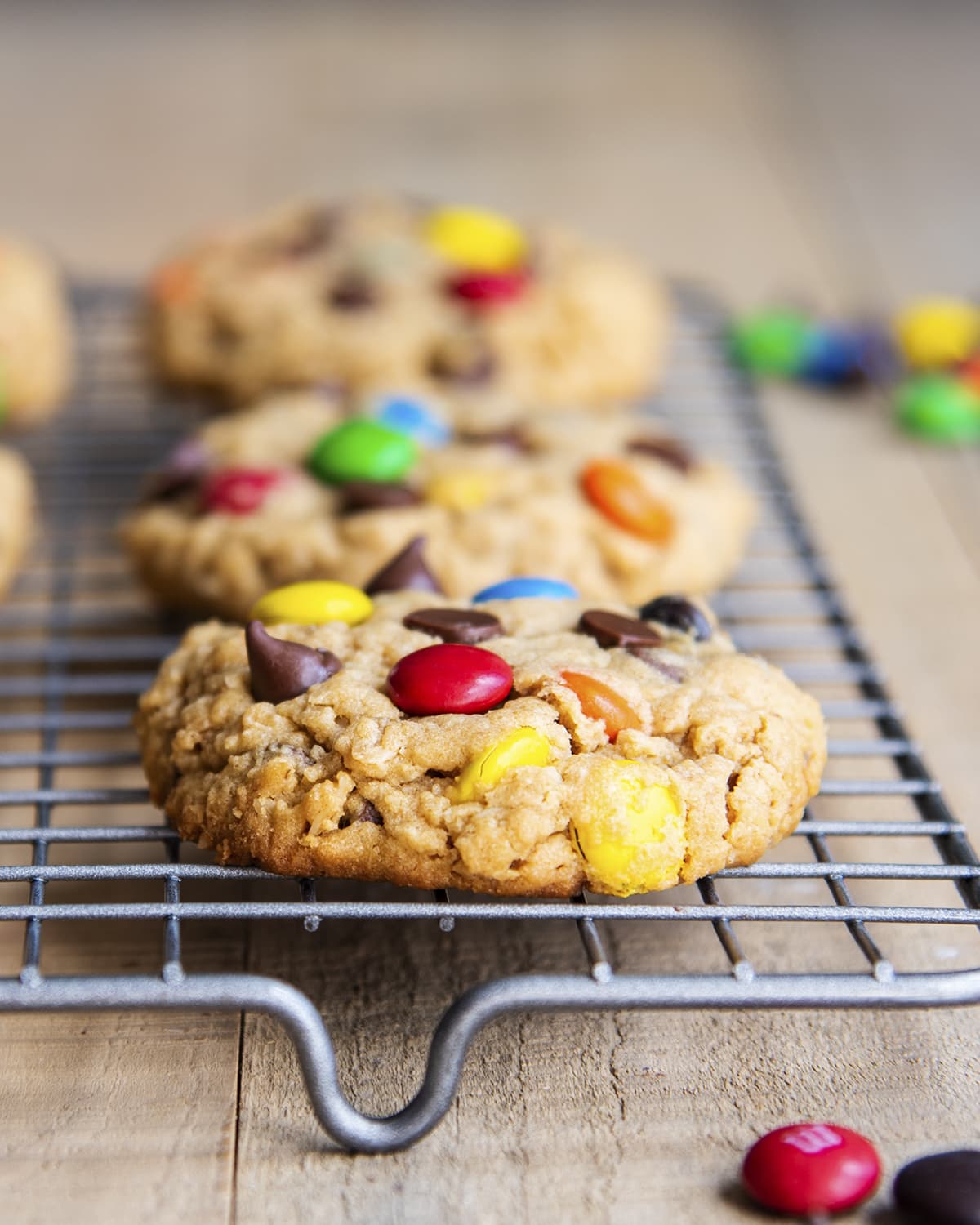 Monster cookies with m&ms on a cooling rack.
