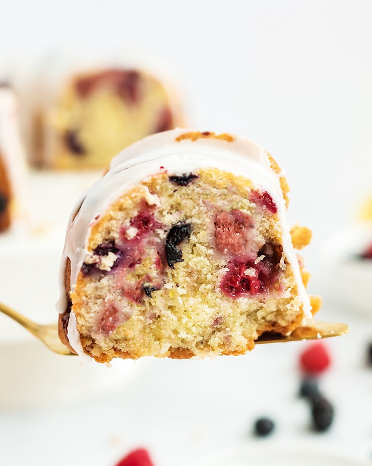 A slice of lemon berry bundt cake on a spatula with berries throughout