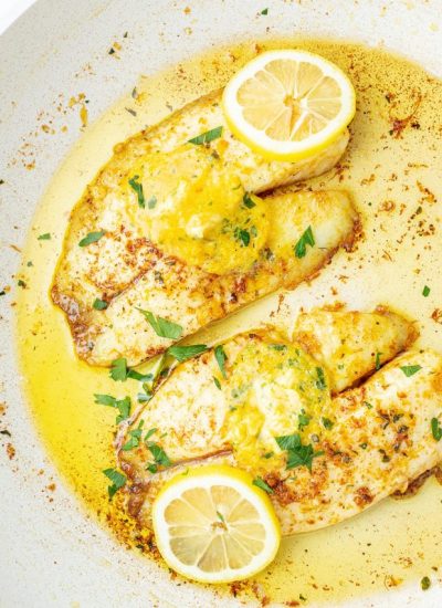 Two Tilapia fillets topped with citrus butter and lemon slices.