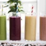 A line of a green smoothie, purple smoothie, yellow smoothie, and pink smoothie.