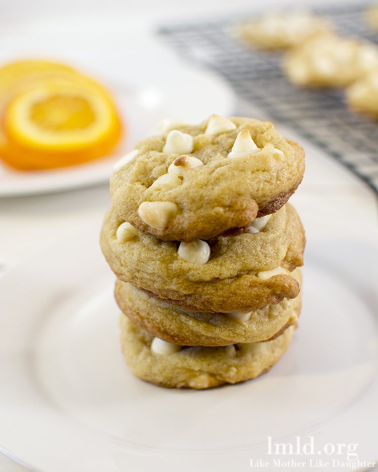 Front view of creamsicle cookies stacked on a white plate.