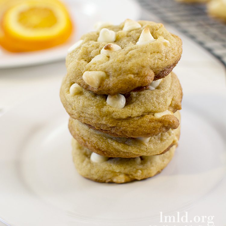 Front view of creamsicle cookies stacked on a white plate.