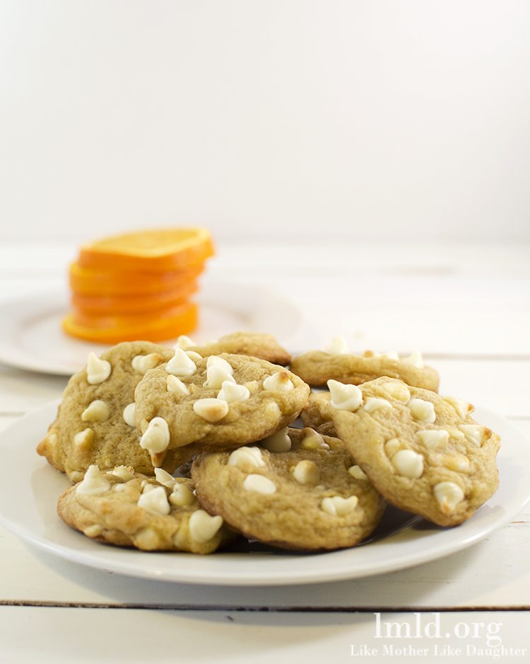 Front view of creamsicle cookies stacked on a white plate.
