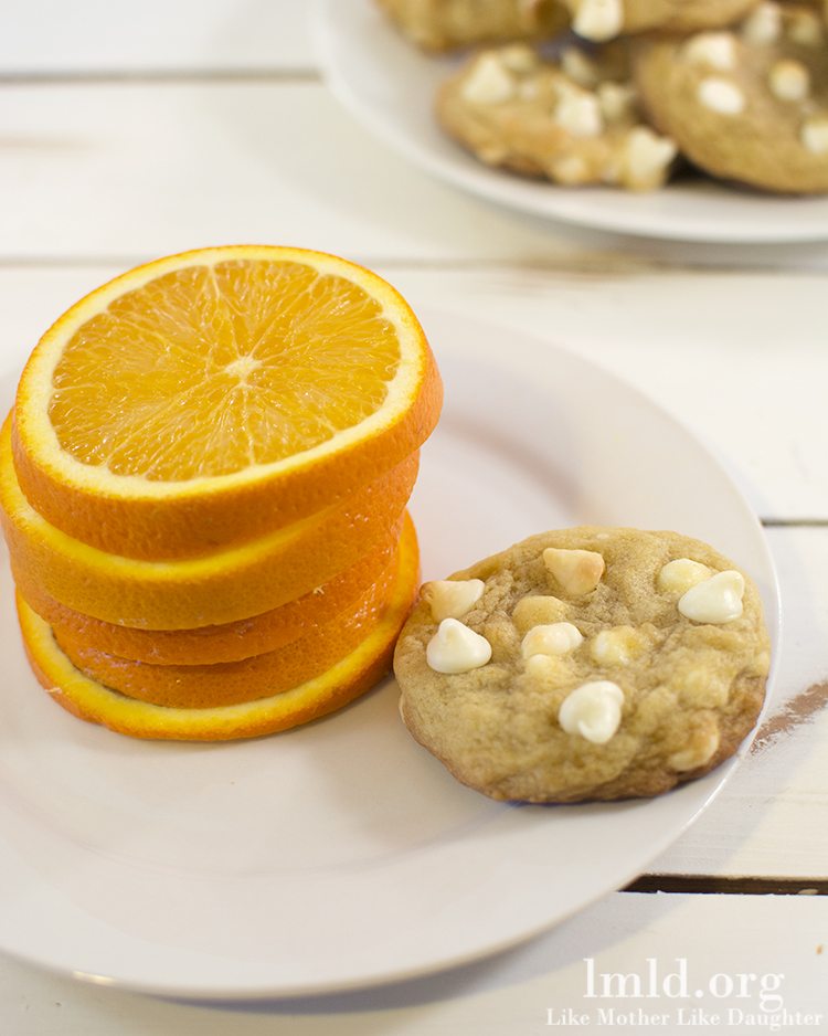 A stack of orange slices next to a creamsicle cookie.