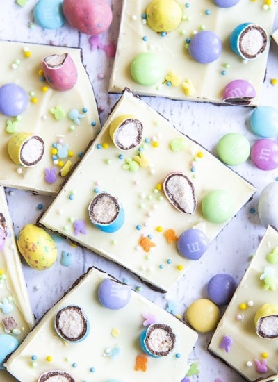 A spread of chocolate bark, topped with white chocolate, covered in chopped up malted eggs, m&ms, and pastel sprinkles.