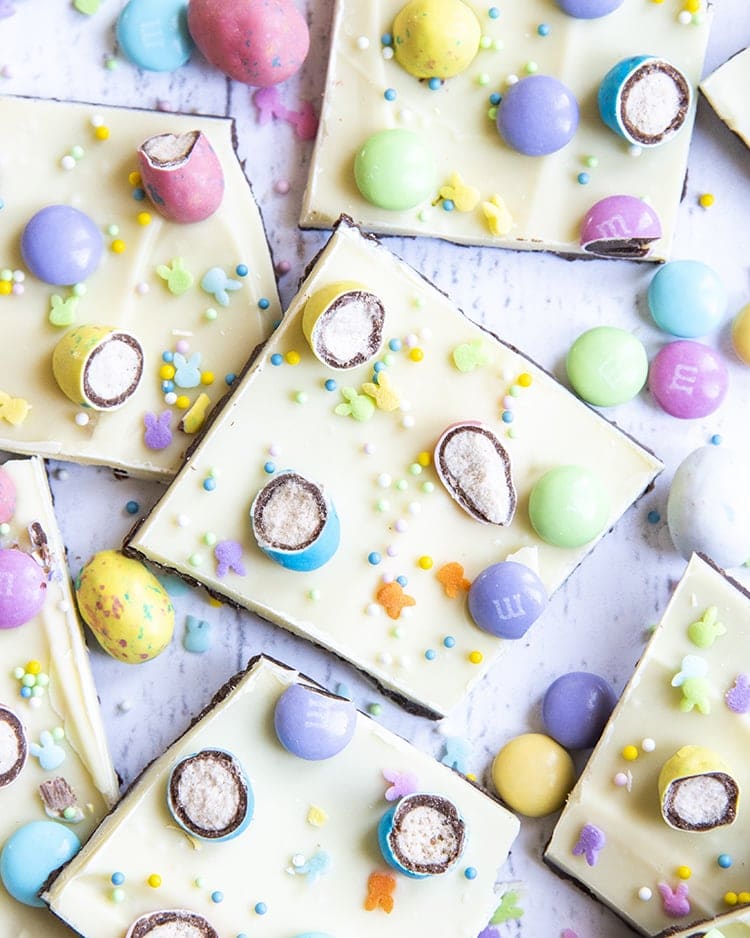 A spread of chocolate bark, topped with white chocolate, covered in chopped up malted eggs, m&ms, and pastel sprinkles.