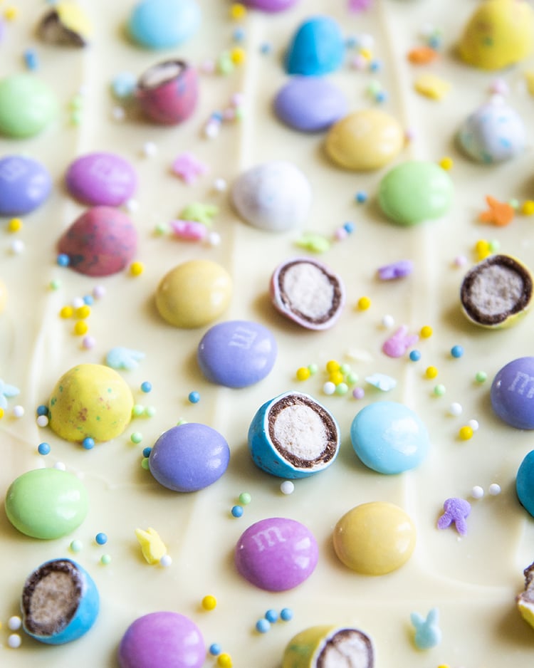 A close up of white chocolate Easter bark, sprinkled with pastel colored Easter chocolates and sprinkles.