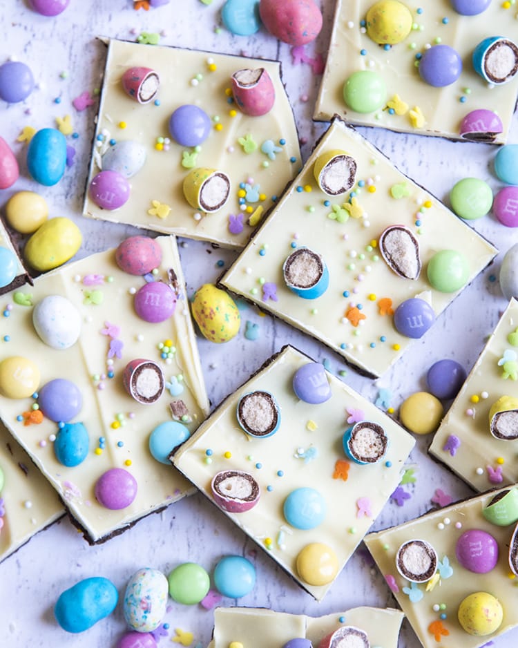 A spread of chocolate bark, topped with white chocolate, covered in chopped up malted eggs, m&ms, and pastel sprinkles.