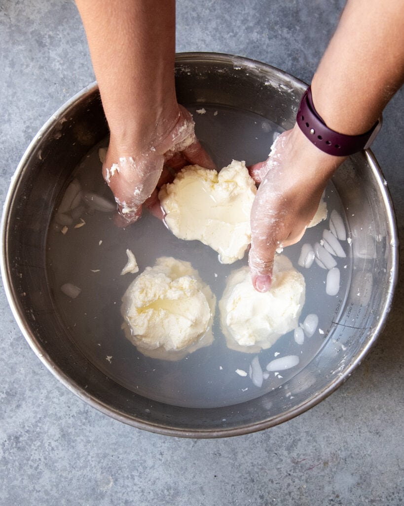 Three balls of butter in a cloudy bowl of ice water.