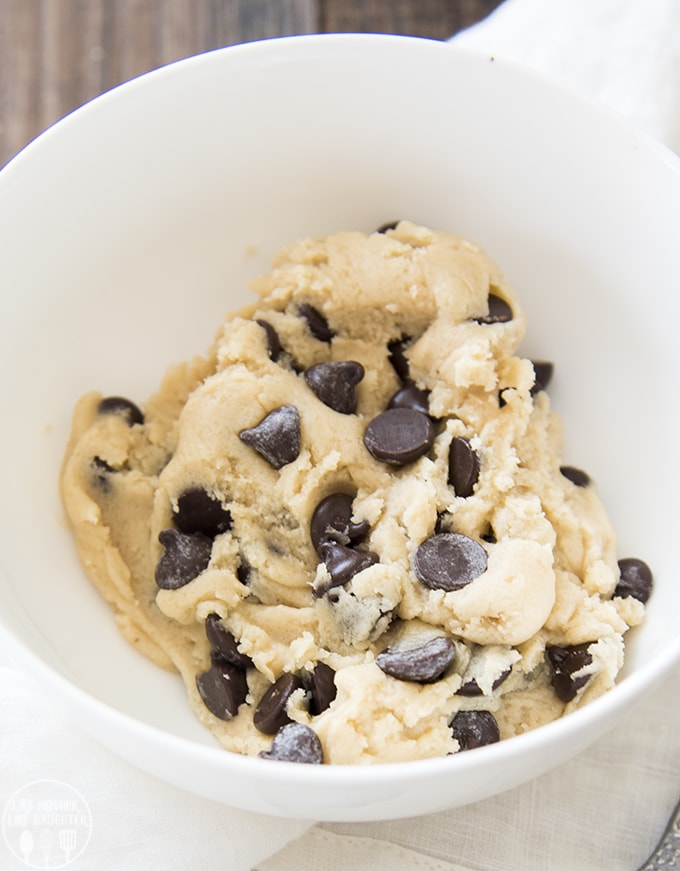 A small bowl full of edible cookie dough with lots of chocolate chips.