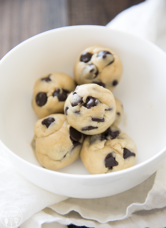 A bowl of 6 small balls of cookie dough. There are lots of chocolate chips peaking through the cookie dough.