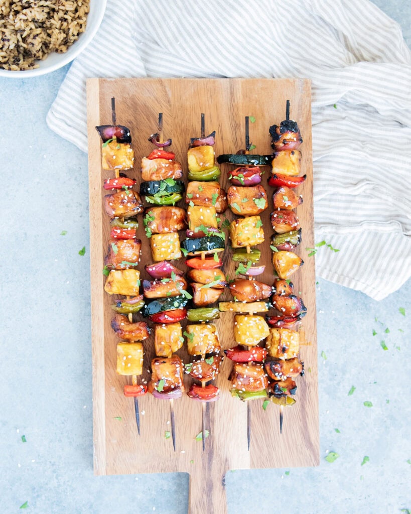 Chicken and veggie kabobs on a wooden board.