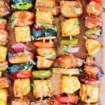 Rows of chicken and veggie kabobs on wooden kabob sticks.