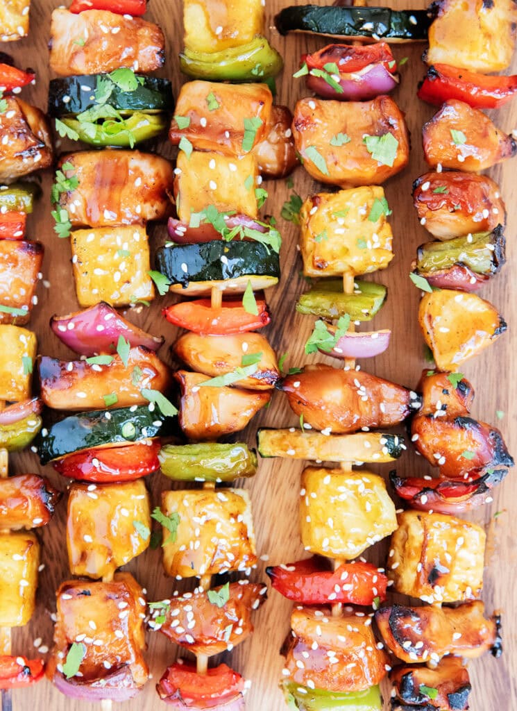 Rows of chicken and veggie kabobs on wooden kabob sticks.
