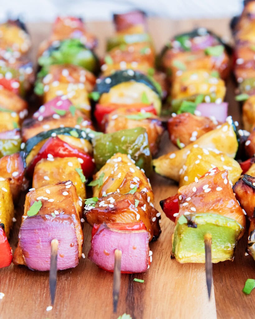 Rows of chicken and veggie kabobs on wooden kabob sticks.