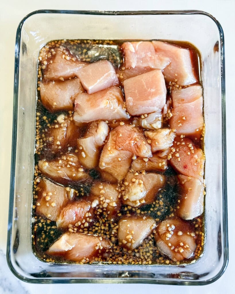 Pieces of chicken marinating in teriyaki sauce.
