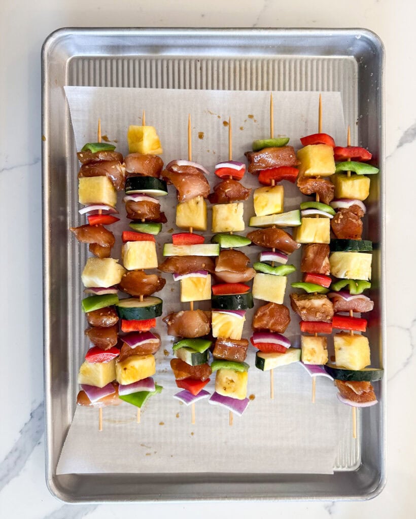 Uncooked chicken kabobs on sticks.