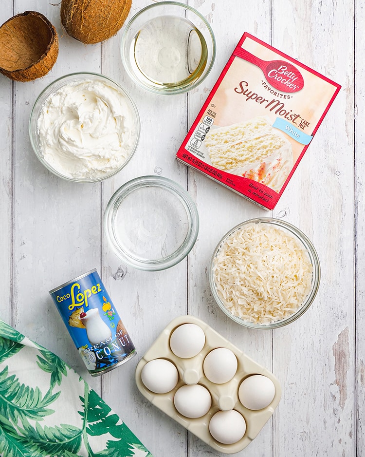 The ingredients needed to make coconut cream poke cake, a boxed mix, cream of coconut, eggs, shredded coconut, oil, water, and whipped cream.
