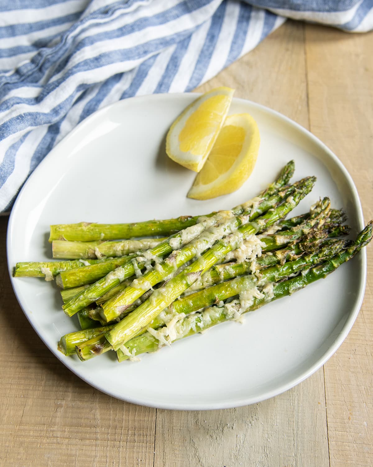 A plate of asparagus stalks topped with shredded parmesan cheese.
