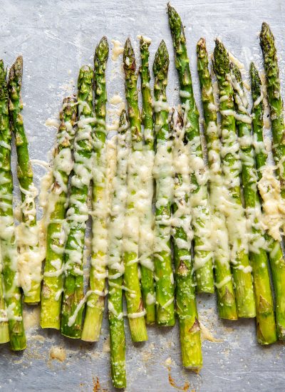 Parmesan asparagus stalks on a baking tray.