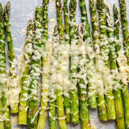 Parmesan asparagus stalks on a baking tray.