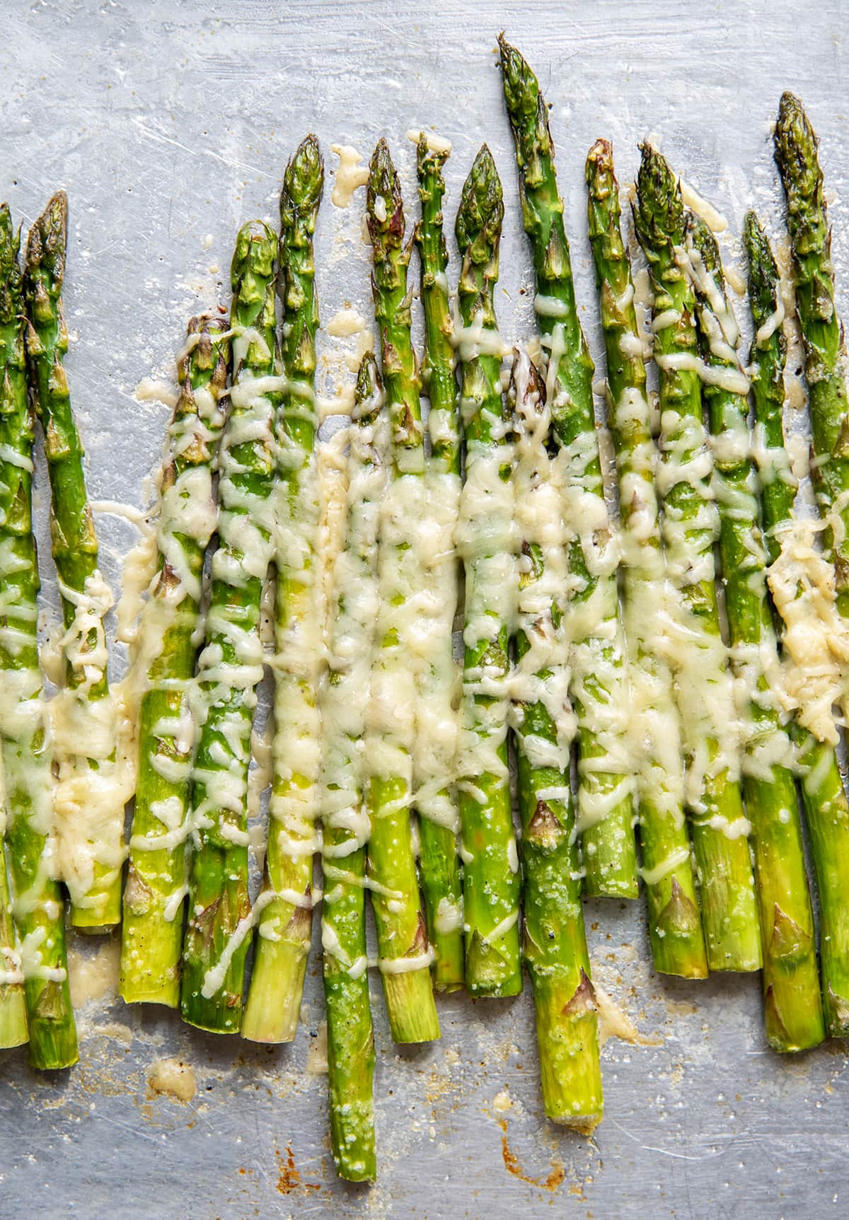 Parmesan asparagus stalks on a baking tray.