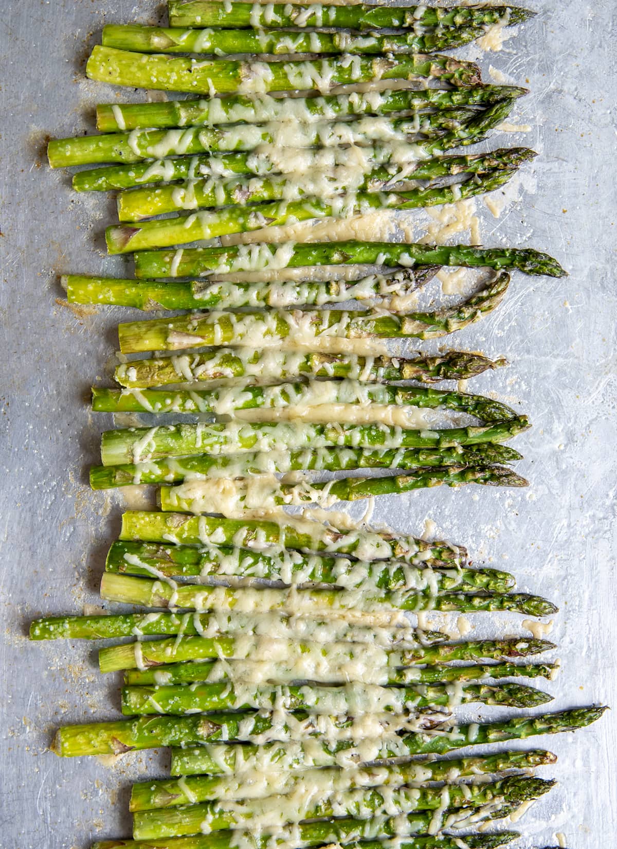An overhead photo of a sheet pan full of parmesan topped asparagus.
