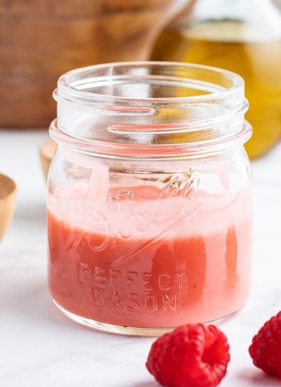 A close up shot of a jar full of raspberry vinaigrette.