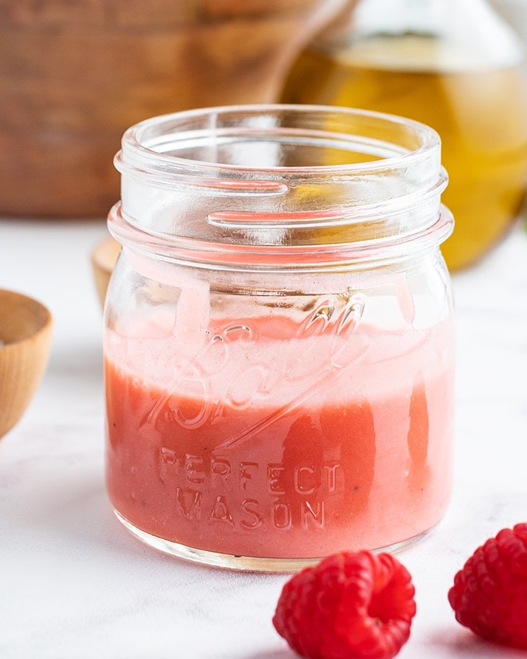 A close up shot of a jar full of raspberry vinaigrette.