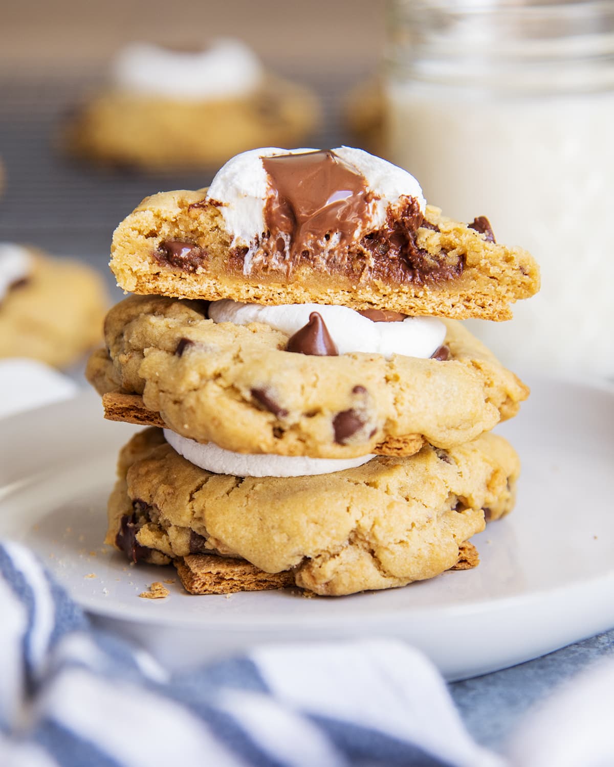 A stack of s'mores cookies and the top cookie is cut in half showing the middle of the cookie.