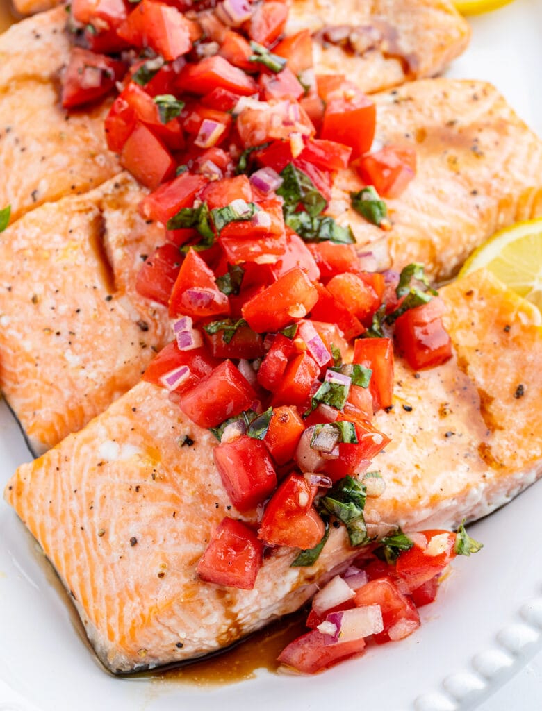 A row of salmon fillets topped with tomato basil relish.