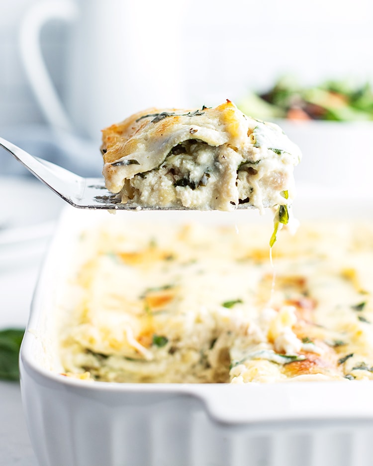 A serving of chicken lasagna scooped out of the pan onto a spatula.