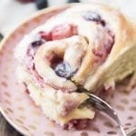 Angled view of mixed berry sweet rolls on a pink plate.