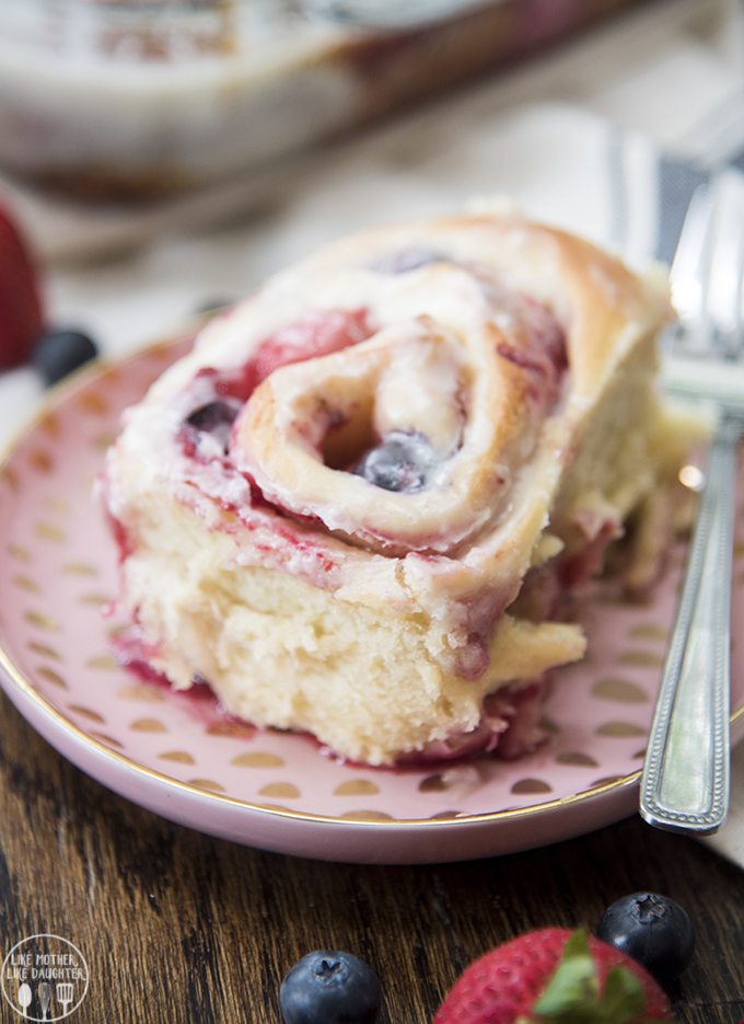 Front view of mixed berry sweet rolls on a pink plate.