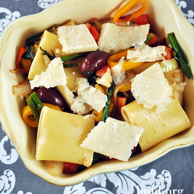 Top view of schiaffoni pasta with vegetables in a creme baking dish.