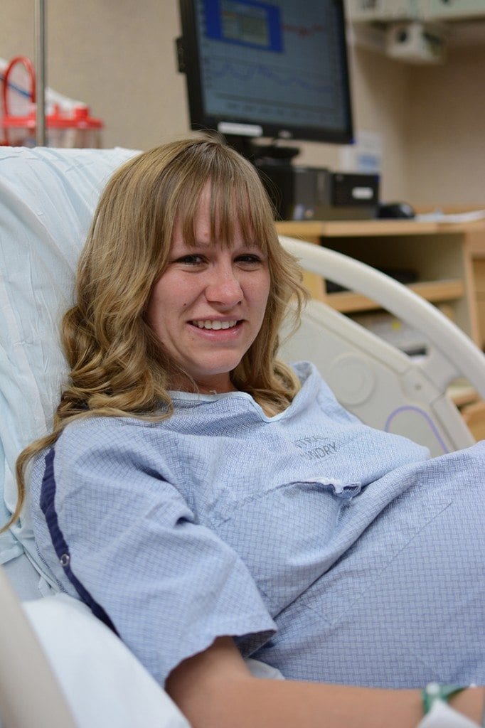 An expectant mother smiles in a hospital bed.