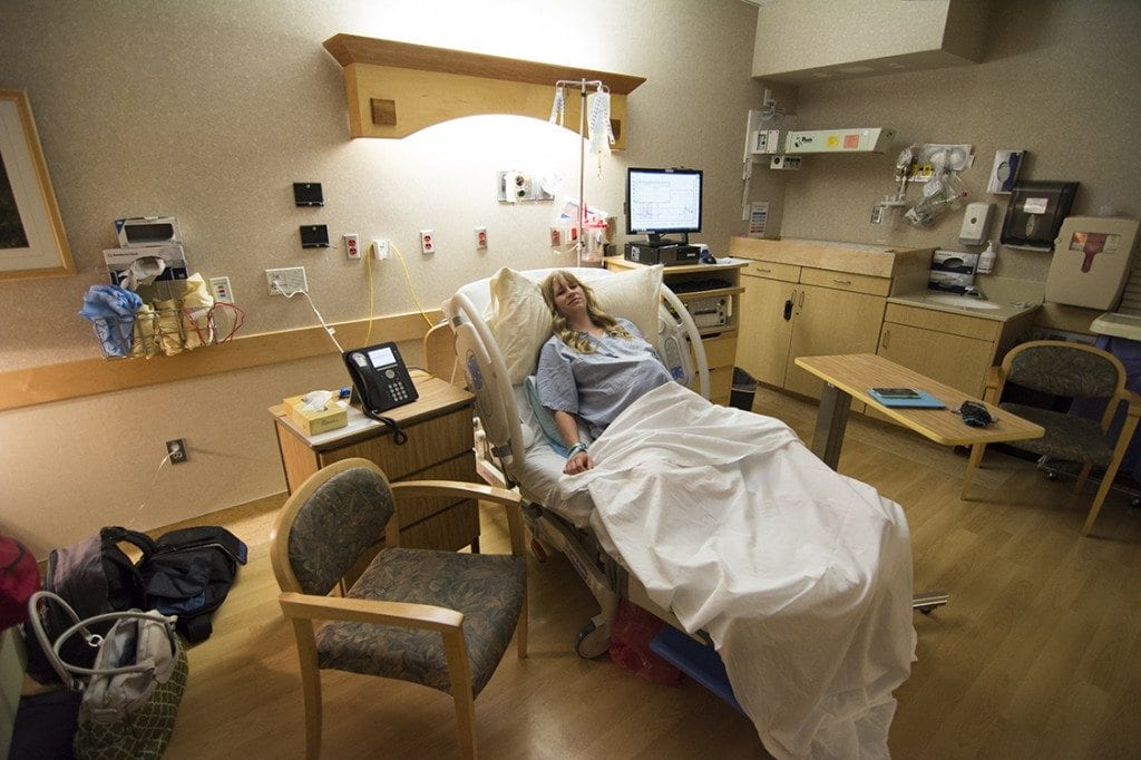 A woman smiles in a hospital as they away a newborn baby.