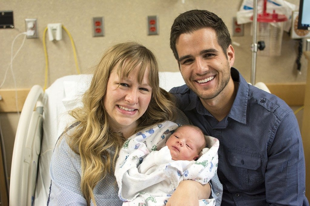 A family smiles together after a newborn boy is born.