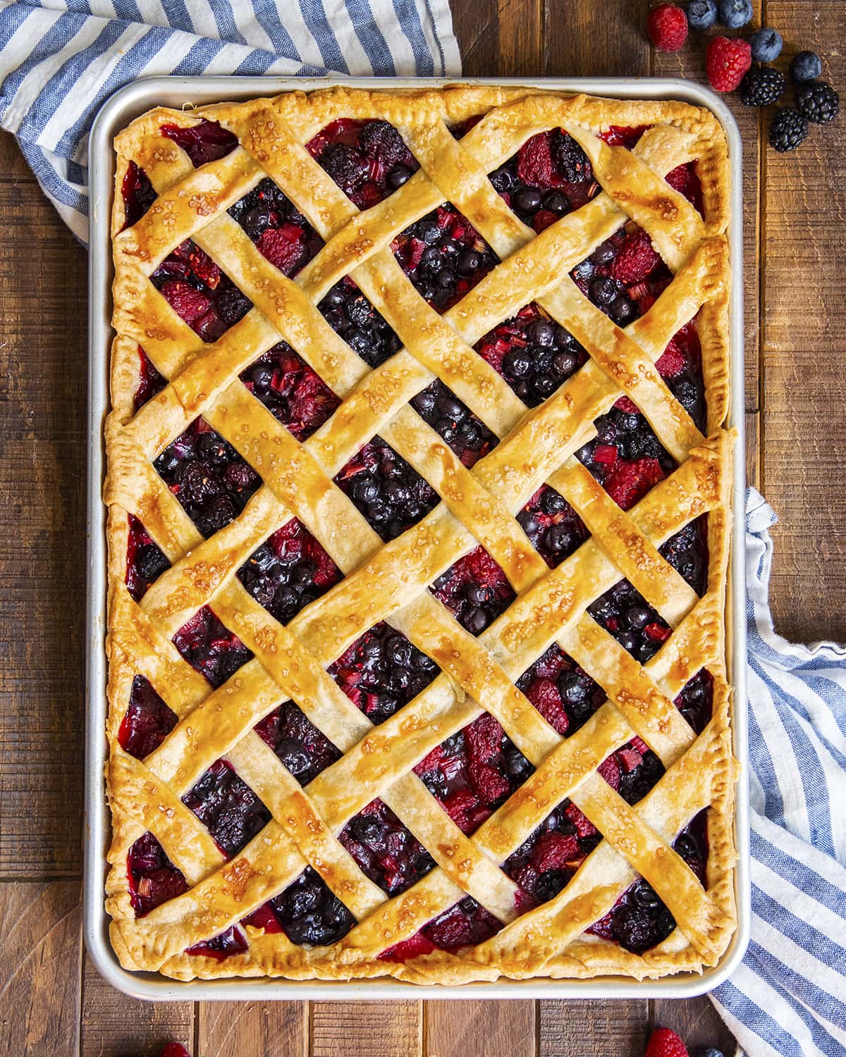 An overhead photo of a berry slab pie in a cookie sheet with a lattice crust on top.