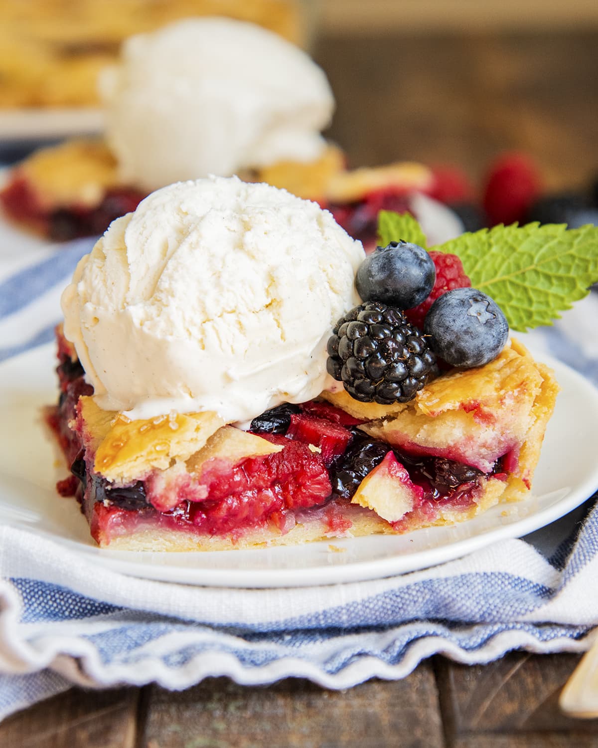 A slice of slab pie on a plate topped with ice cream and fresh berries.