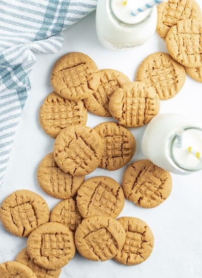 Close up image of flourless peanut butter cookies laying next to each other with a glass of milk.