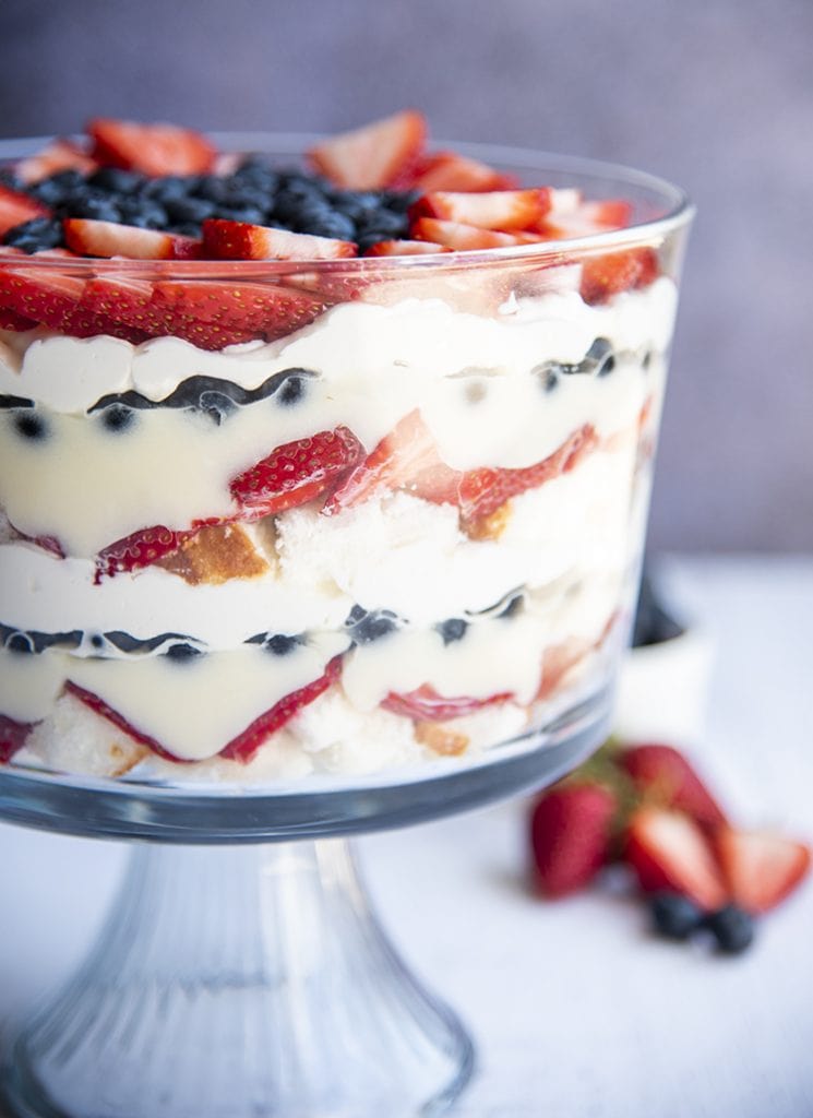 A red white and blue trifle with layers of angel food cake, strawberries, pudding, blueberries, and whipped cream